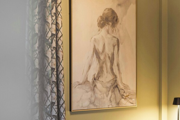Una obra de arte enmarco que muestra una figura sentada en una silla, con una cortina estampada a la izquierda.