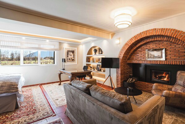 A cozy living room with a fireplace, leather sofas, a coffee table, and a desk with a chair.