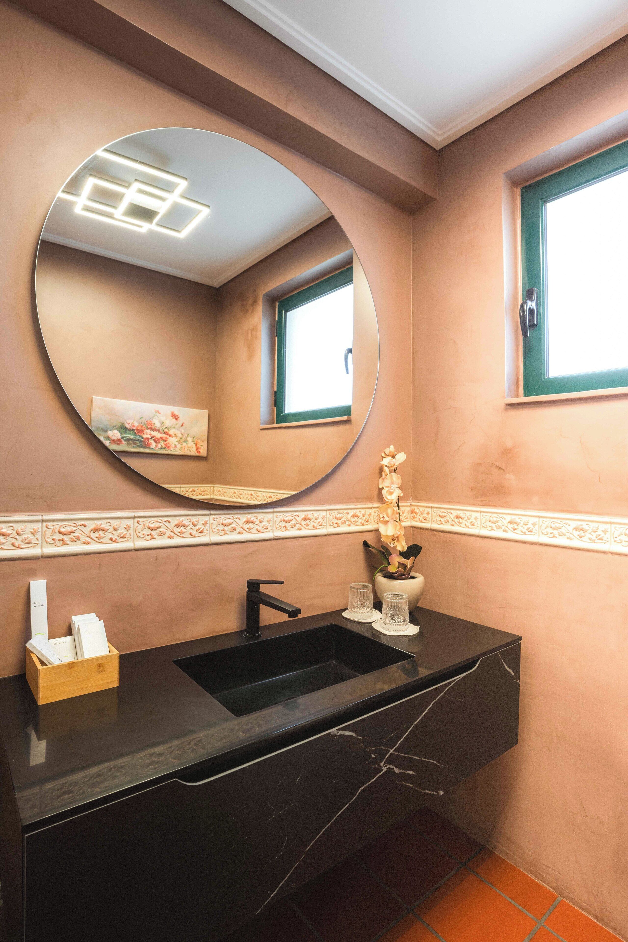 A bathroom with a black sink, a mirror, and a window.