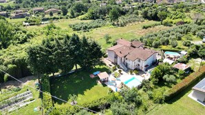 Un'ampia casa con piscina, immersa nel verde e circondata da un paesaggio collinare.