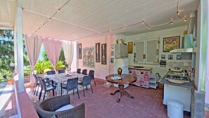 Una veranda riparata con tavolo, sedie e luci decorative.
