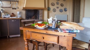 A cozy kitchen with a dining table, a coffee machine, and a variety of dishes. - Cosy apartment for 3 people with WIFI, pool, A/C, TV and pets allowed (Isola Di Fano)