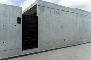 Ein Gebäude aus Beton mit einem schwarzen Tor und einem Schild mit der Nummer 9.