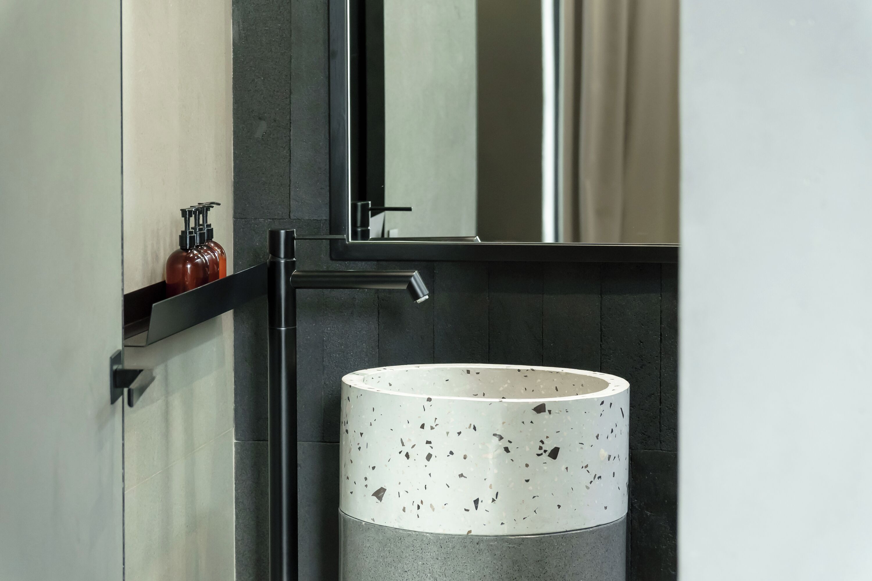 Une salle de bain dotée d’un lavabo moderne, d’un miroir et d’une étagère où sont rangés les articles de toilette.