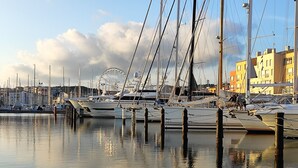 A marina with boats docked, a Ferris wheel in the background, and buildings along the waterfront. - CAP D'agde, Agréable 2 Pièces 42m2, Loggia, 4 Voyageurs, 300m Plage du Môle (Agde)