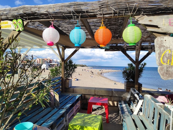 A beachside café with wooden furniture and hanging paper lanterns.