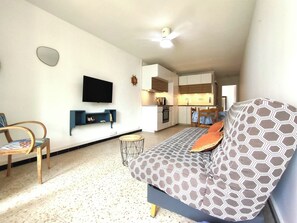 A living room with a sofa, a TV, a small table, and a chair.