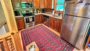 A cabin kitchen with wooden cabinets, a stainless steel refrigerator, a microwave, an oven, and a sink. - Bearly Behaving | 3BR Cabin w/ Hot Tub, Pool Table, Fire Pit (Todd)