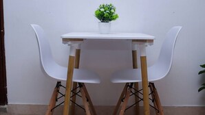 Een eettafel met twee witte stoelen en een bloempot erop.