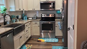 A modern kitchen with white cabinets, stainless steel appliances, and a wooden floor. - HO HO HO! Holiday Discount (Franklinton)