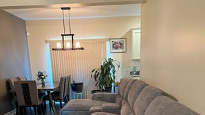 A modern living room with a sectional sofa, dining table, chairs, and a potted plant. - HO HO HO! Holiday Discount (Franklinton)