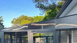 A covered patio with a wooden deck, a sliding glass door, and a view of a house in the background. - HO HO HO! Holiday Discount (Franklinton)