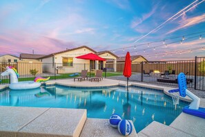 Un jardin avec une piscine, des jeux gonflables et un espace salon extérieur.
