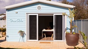 A light blue house with a 'Casa Blu' sign, a sliding glass door entrance, a 'Welcome' mat, and a large potted plant.