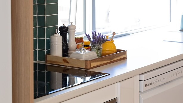 A kitchen with a window, a wooden shelf with kitchen items, and a dishwasher.