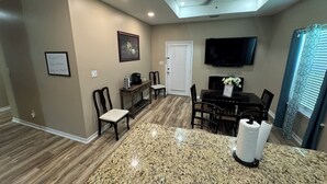 A dining area with a granite countertop, a ceiling fan, a television mounted on the wall, and a door with a window. - Cottage near the beach , owa, Bucees , King bed , WiFi quiet neighborhood  (Loxley)