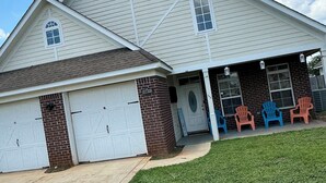 A two-story house with a garage, a covered porch with plastic chairs, and a well-maintained lawn. - Cottage near the beach , owa, Bucees , King bed , WiFi quiet neighborhood  (Loxley)