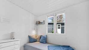 A bedroom with a single bed, a white dresser, a shelf with books, and a window with shutters. - "Synnöve" - 350m from the sea by Interhome (Væggerløse)