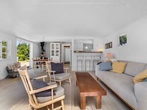 A spacious living area with a sofa, chairs, a wooden coffee table, and a dining area with a table and chairs.