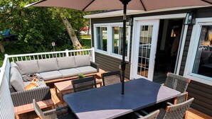 Una terraza al aire libre con una mesa y sillas, un sofá y un paraguas grande.