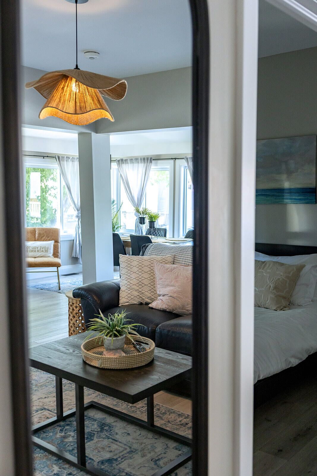 A modern living room with a sofa, coffee table, and a hanging light fixture.