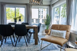 Un salon moderne avec un coin repas, de grandes fenêtres et une vue sur la ville.