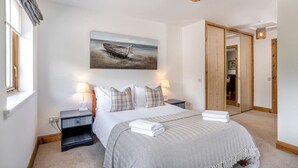 A bedroom with a bed, bedside tables, a painting, and a wardrobe. - Dormie Cottage, spacious bungalow with log fire! (Aberdeenshire)