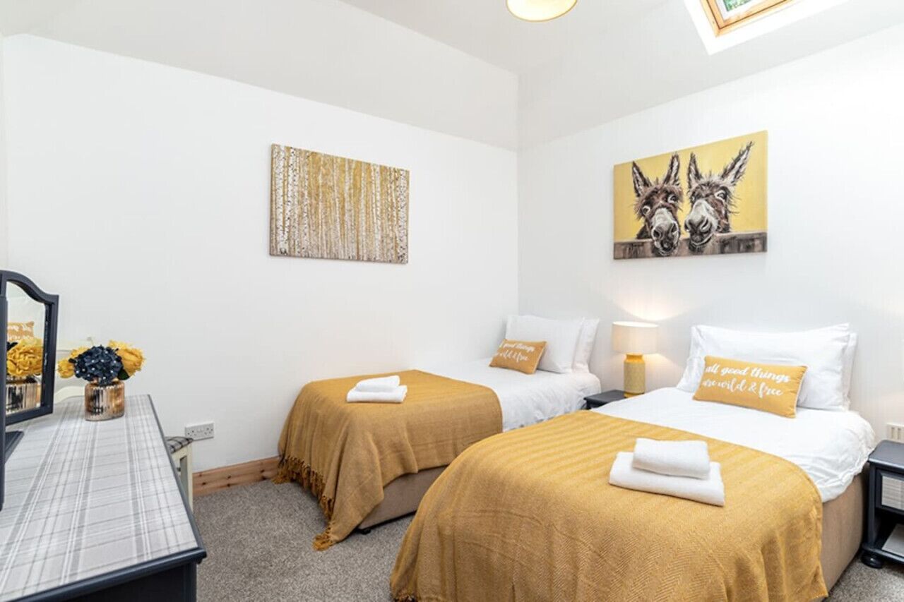 A hotel room with two beds, a desk with a mirror, and artwork on the walls.