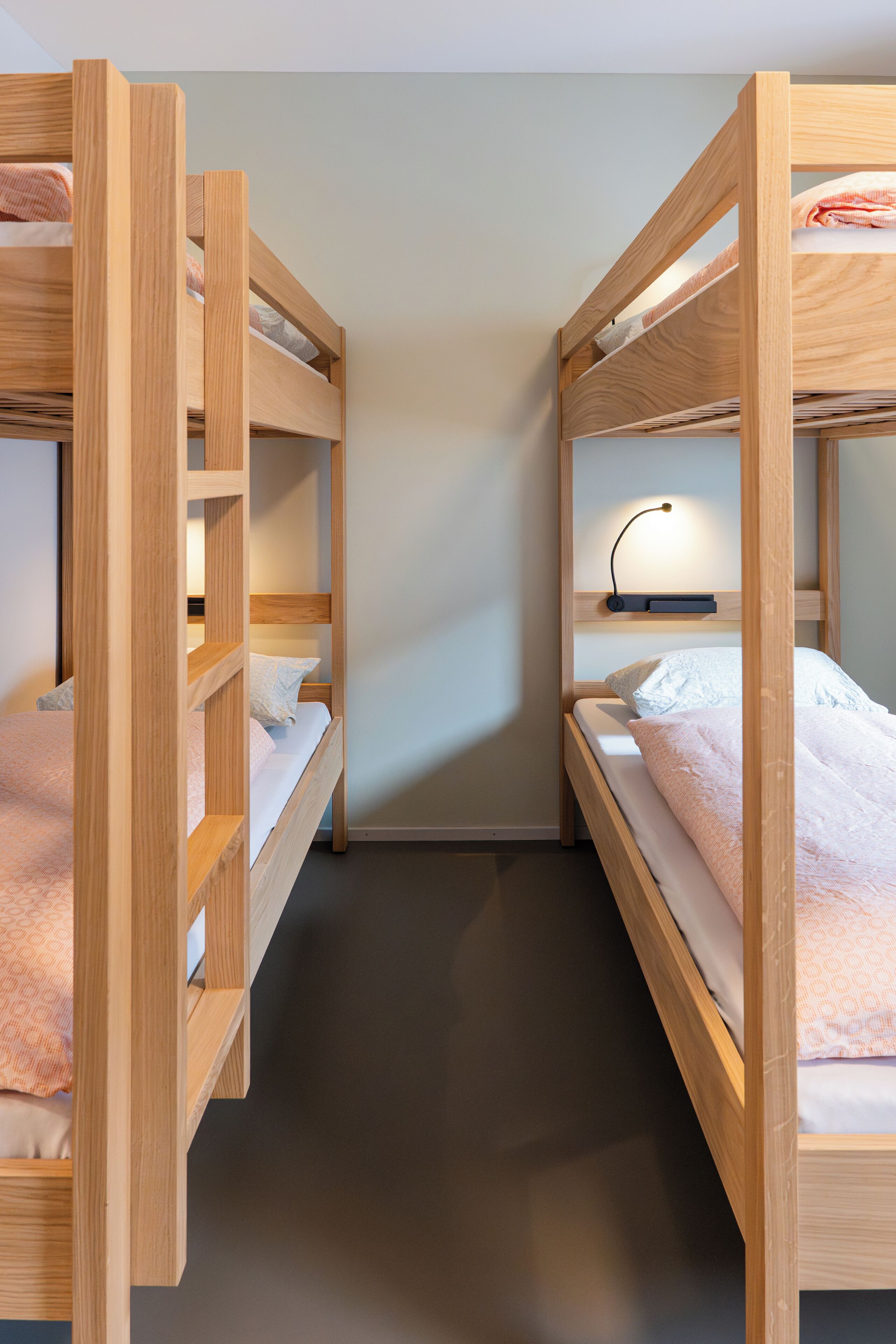 Een slaapkamer met een stapelbed, nachtkastje en lamp.