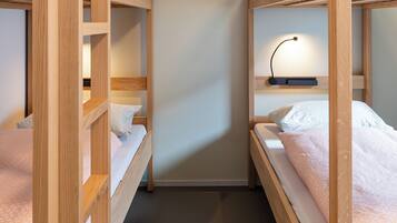 Een slaapkamer met een stapelbed, nachtkastje en lamp.