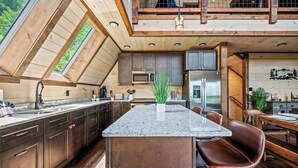 A modern kitchen with a central island, dark wooden cabinets, and a skylight.