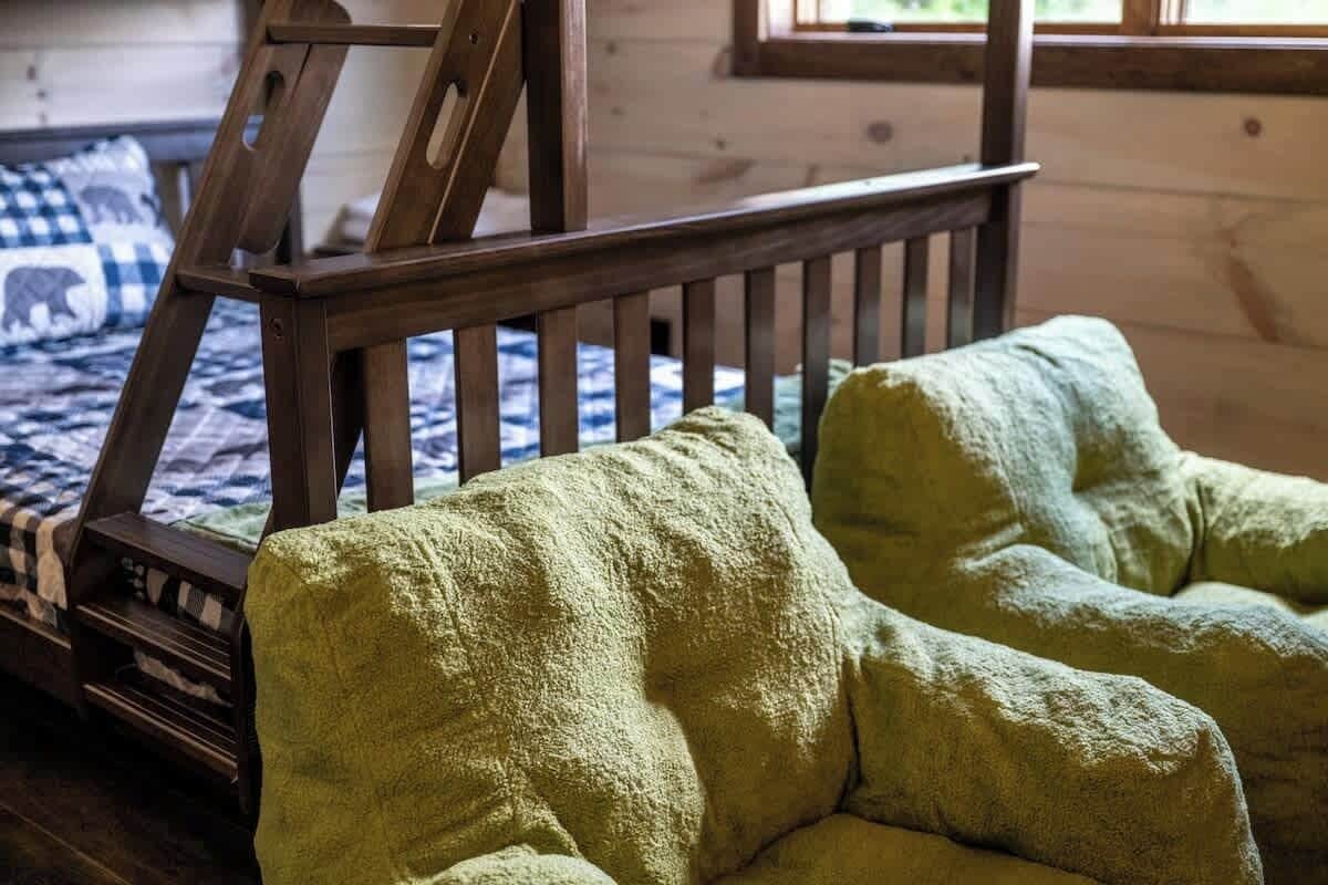 A wooden bed frame with a slatted headboard, a quilted bedspread, and a green, textured throw blanket on the bed.