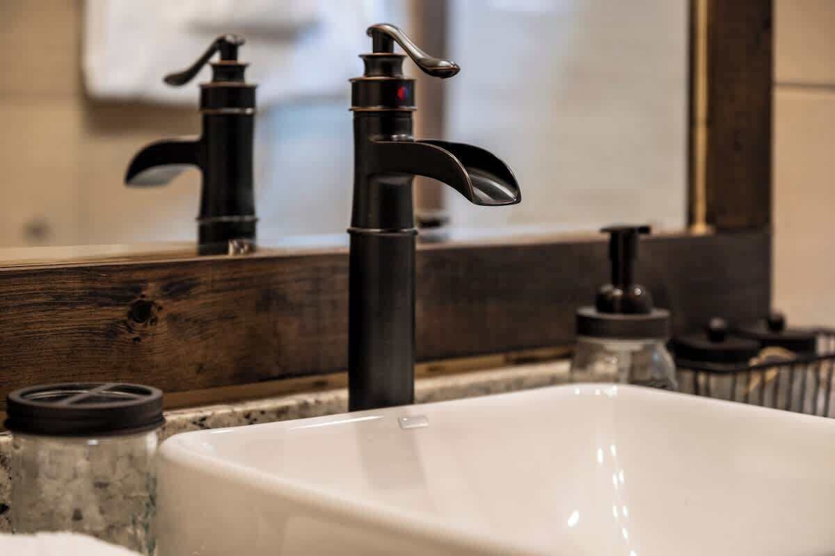 A bathroom with a white sink, black faucet, and a wooden countertop.