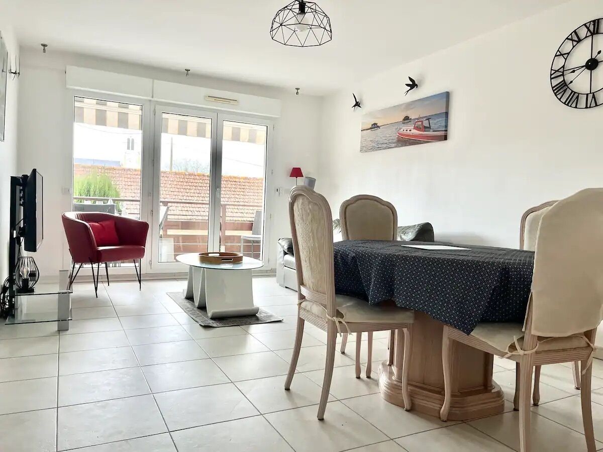 Un coin repas avec une table dressée pour deux personnes, une chaise rouge et une chaise blanche.