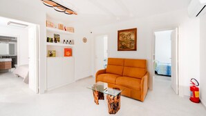 A modern living room with a sofa, a glass coffee table, and a bookshelf. - La Minucciola (Anacapri)