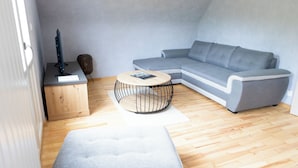 A modern living room with a grey sectional sofa, a round coffee table, and a wooden cabinet.