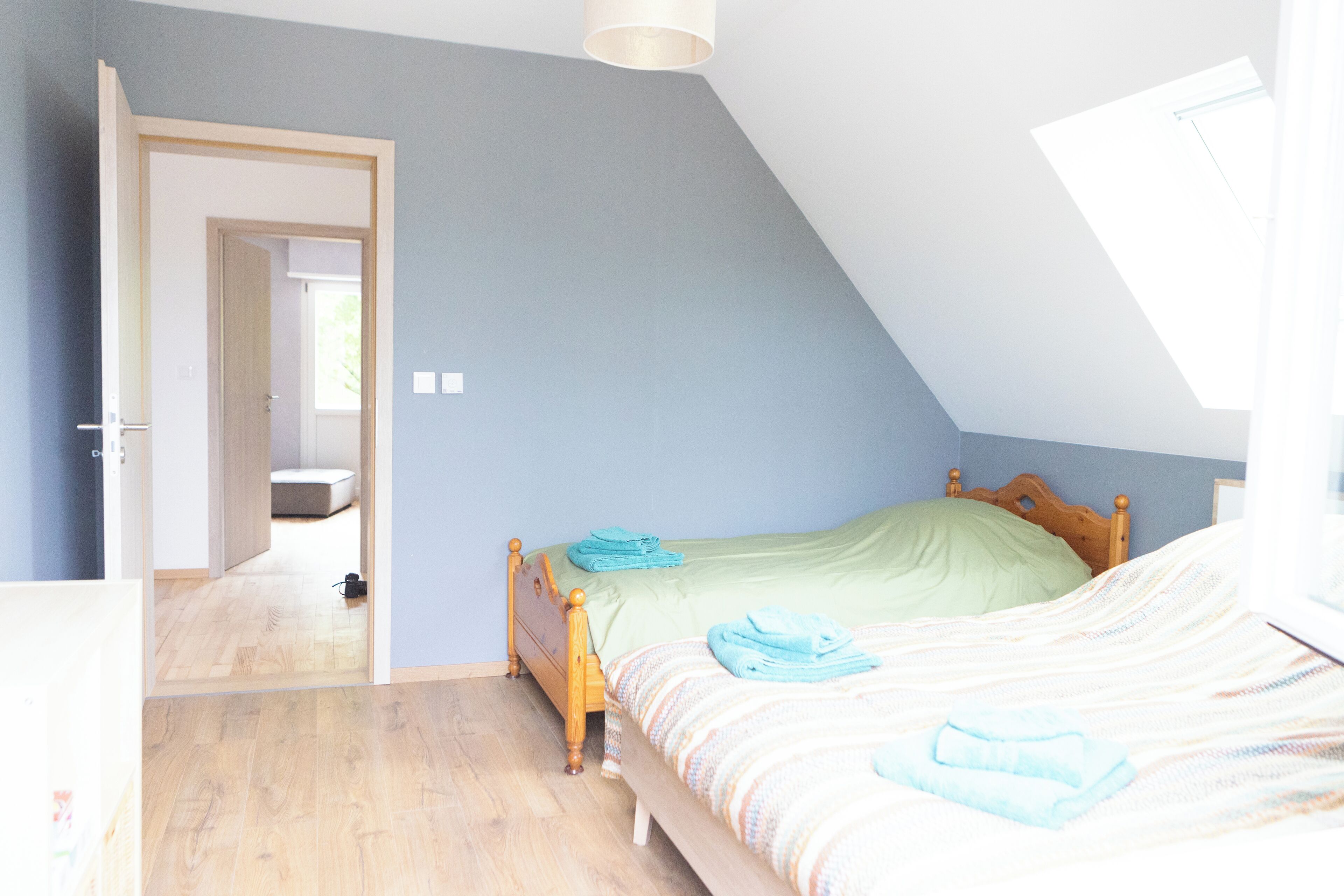 A bedroom with a sloped ceiling, a wooden bed, and a visible door leading to another room.