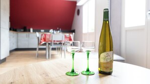 A bottle of wine and two glasses on a table in a room with a red wall and a window.
