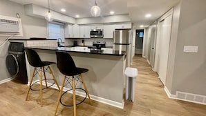 Une cuisine moderne avec un îlot central, des tabourets de bar et un lave-linge.