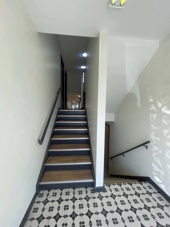 A staircase with wooden steps and a black handrail, leading to an upper floor. - Modern Apartment Near UNMC & Walkable Dining (Omaha)