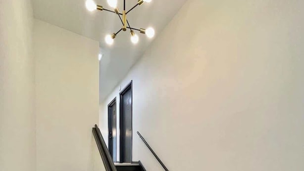 A modern interior with a staircase, wooden flooring, and a contemporary light fixture.