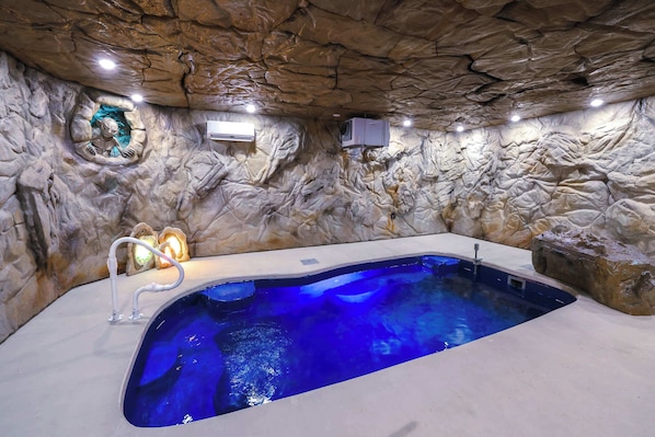 A spa area with a hot tub, stone walls, and a small window. - Lord of the Rings: Pool, Theater, Game Rm, Firepit (Sevierville)