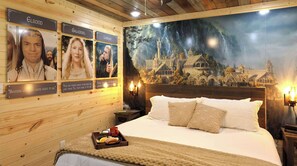 A bedroom with a bed, a nightstand, a tray with food, and a mural of a castle.
