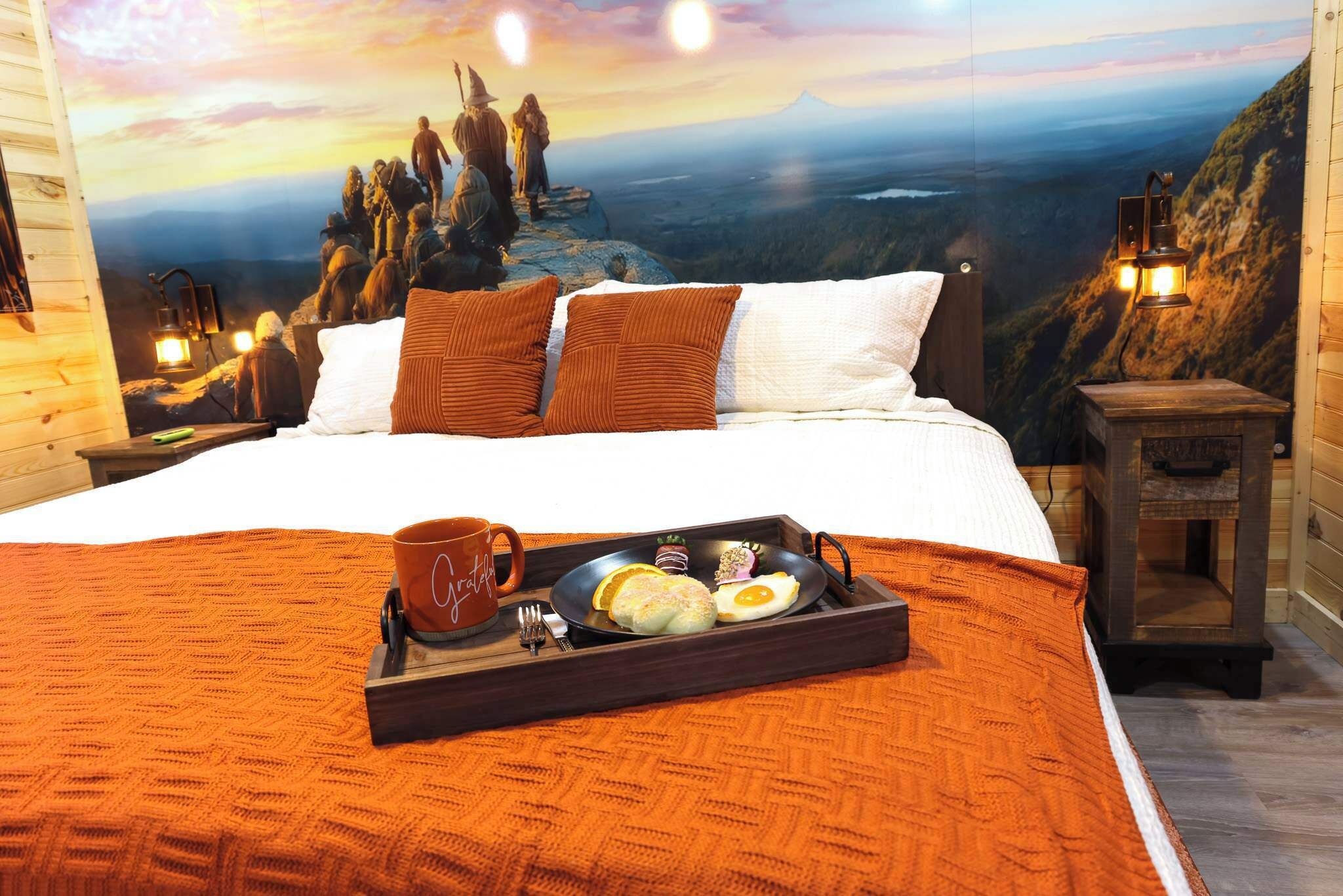 A bedroom with a large bed, a tray with breakfast, and a scenic wall mural.