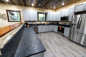 A modern kitchen with wooden cabinets, stainless steel appliances, and a granite countertop. - Lord of the Rings: Pool, Theater, Game Rm, Firepit (Sevierville)