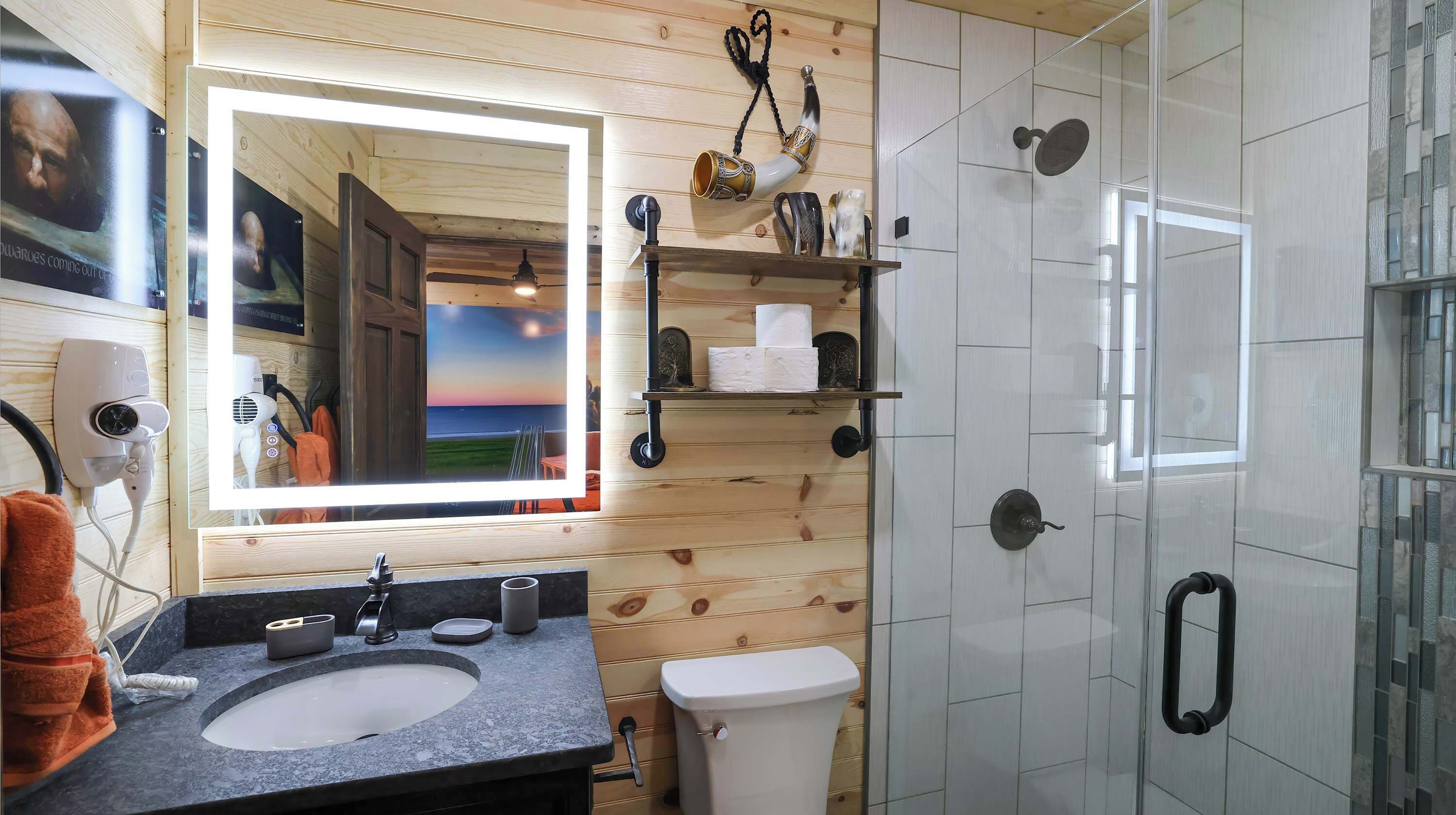 Un baño con detalles de madera, un espejo grande, un lavabo, un inodoro y una zona de ducha.
