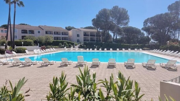 A swimming pool with lounge chairs, surrounded by buildings and trees. - PLEASANT LITTLE STUDIO IN SAINT-RAPHAËL  (Saint-Raphaël)