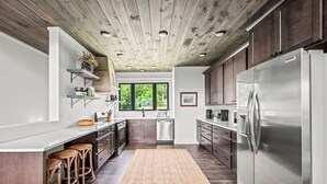 Eine moderne Küche mit Holzboden, Edelstahlgeräten und einem großen Fenster.
