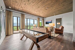 Una habitación amplia con mesa de billar, sofá, sillón y televisor.