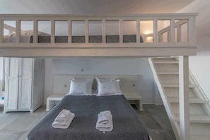 Habitación con literas y una escalera que lleva a un nivel superior. Hay dos almohadas en la cama inferior y dos toallas en el suelo.